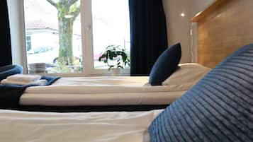 Un dormitorio con cama, ventana, planta y vistas al exterior.