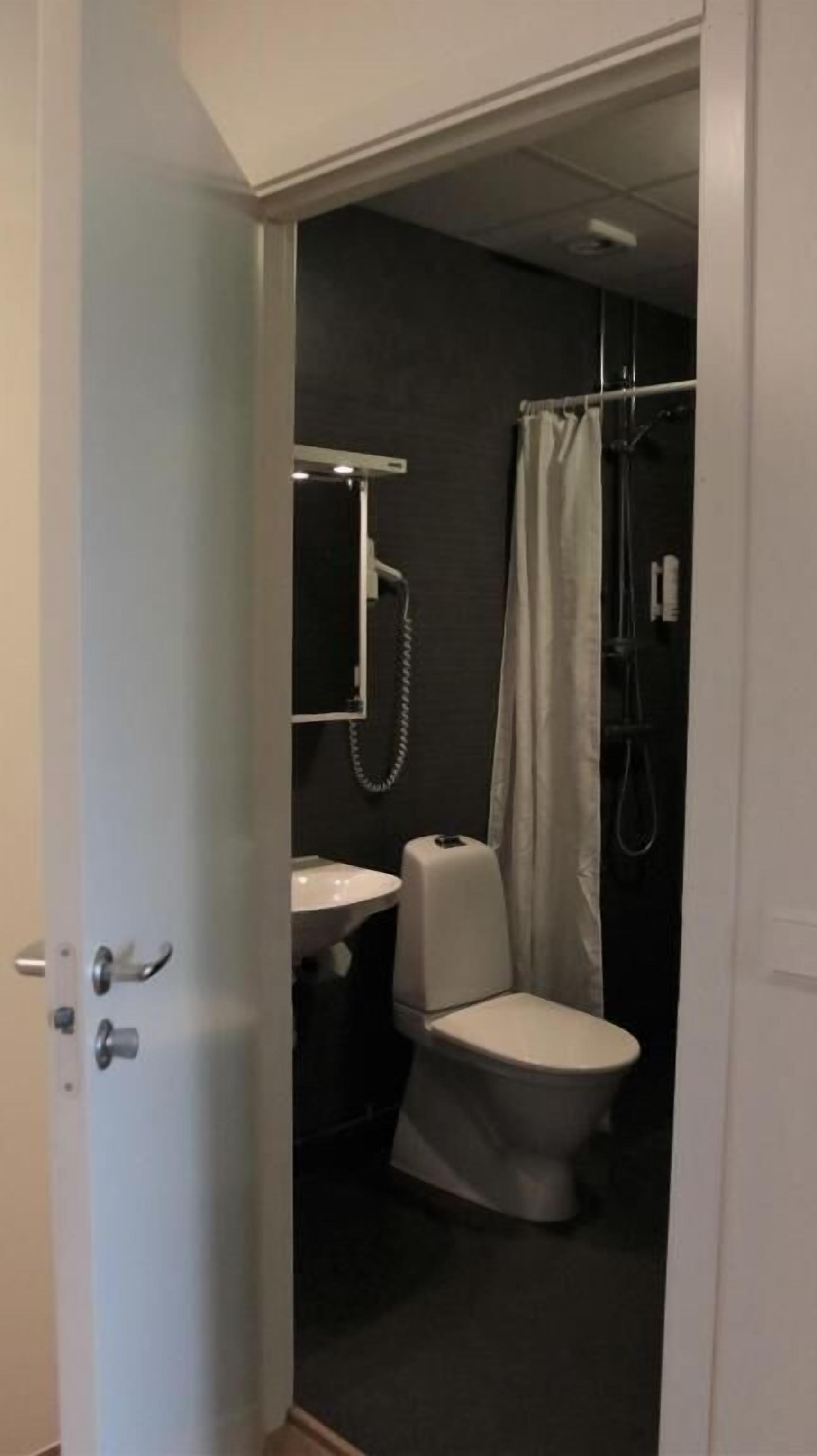 A small bathroom with a toilet, sink, and shower curtain.
