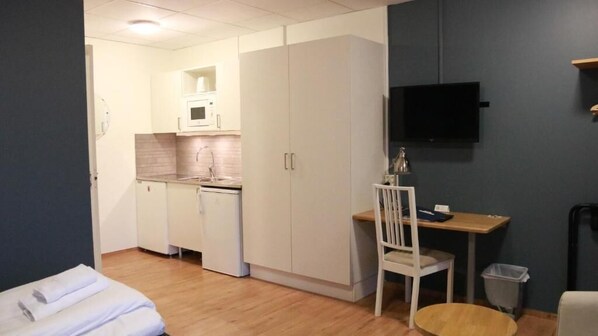 A compact room with a kitchenette, a desk, and a chair. - Lygnerns Pensionat & Konferens (Satila)
