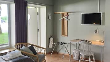 A hotel room with two beds, a desk, a chair, a TV, and a window with curtains.