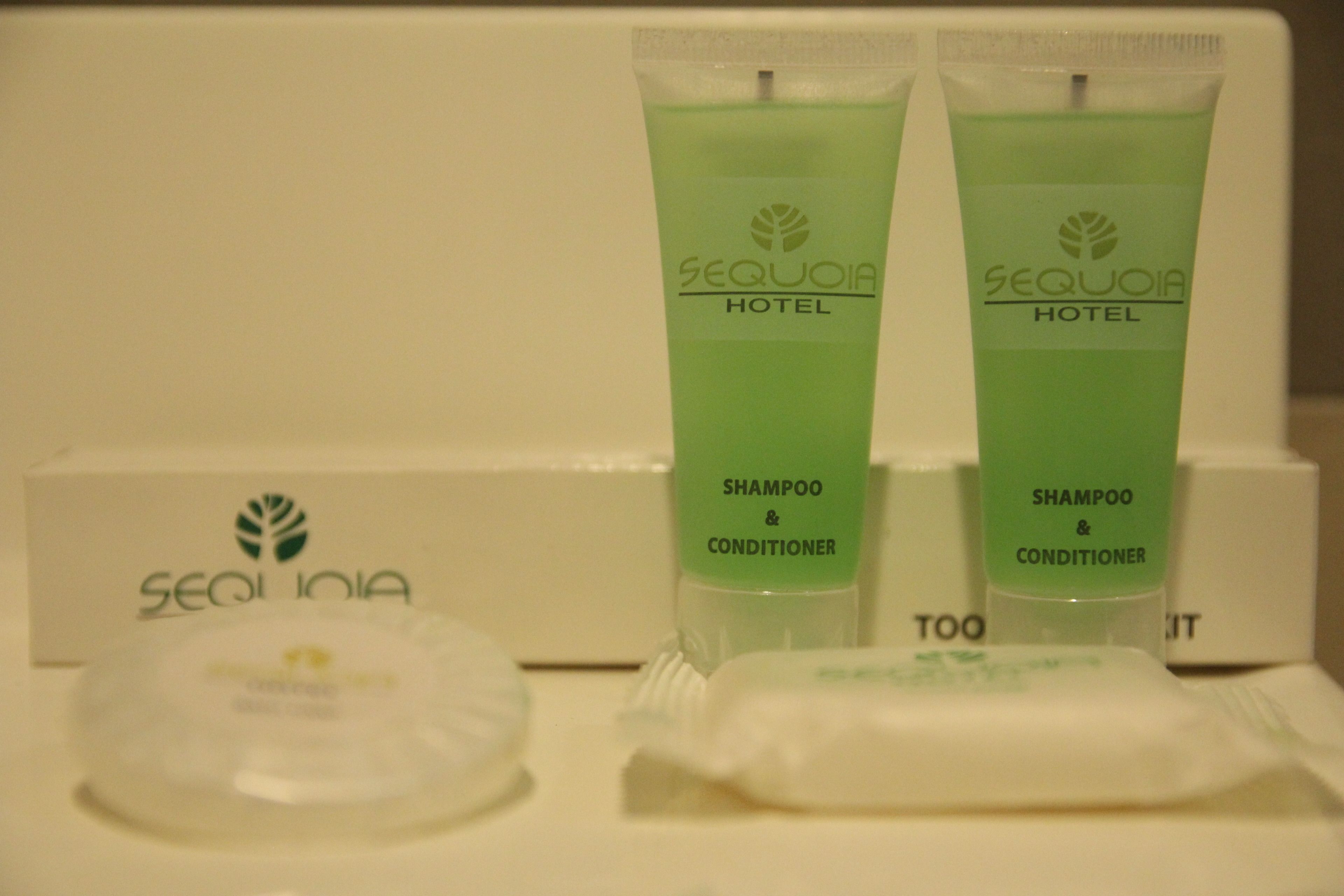 Toiletries including two green bottles labeled 'Sequoia Hotel Shampoo & Conditioner' and a white box with the same branding.