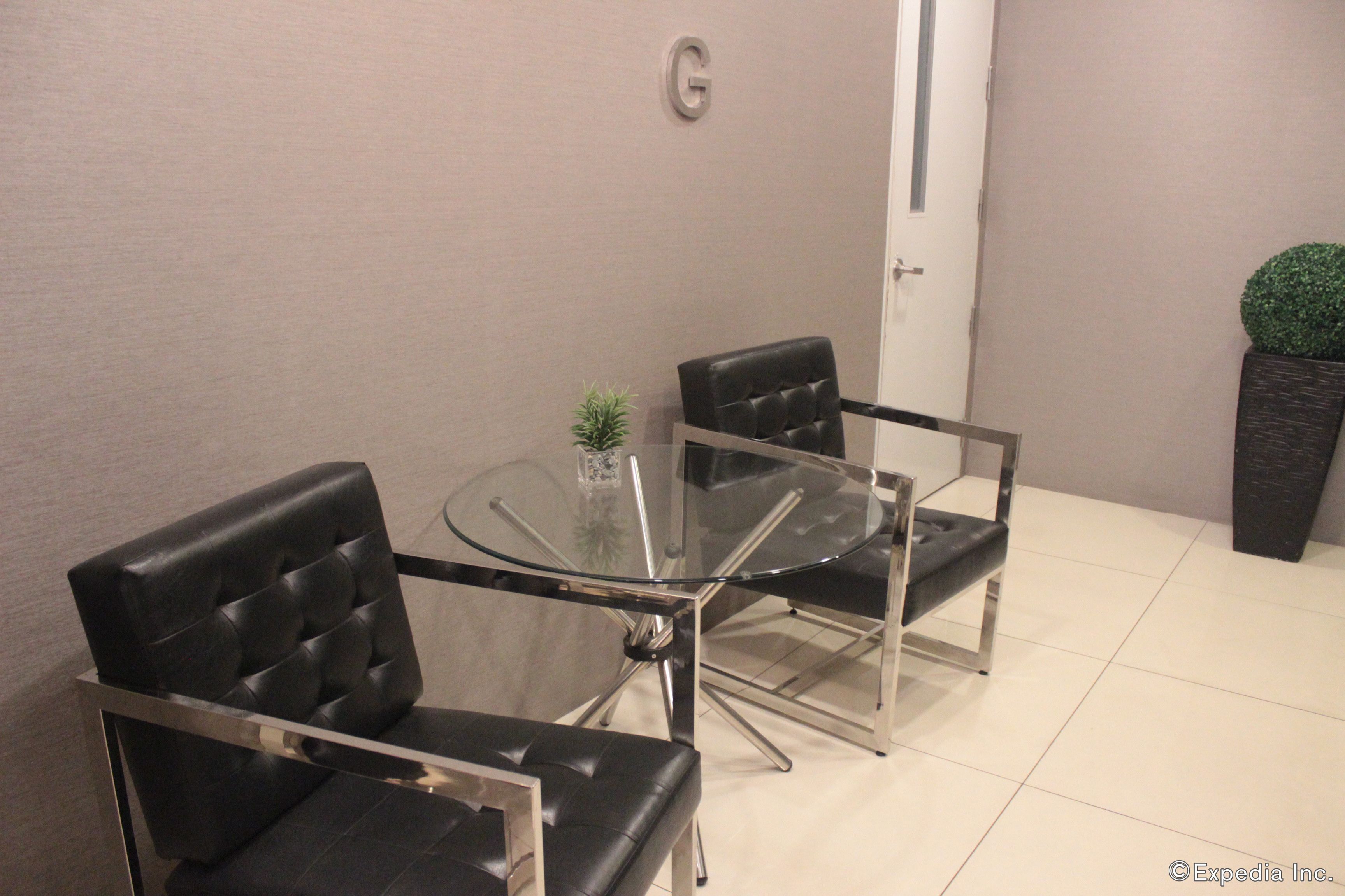A modern meeting room with a glass table and four black leather chairs.