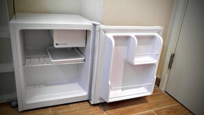 A compact white refrigerator with a freezer compartment on top and a main door with a shelf. - Nuts Hotel (Kowloon)