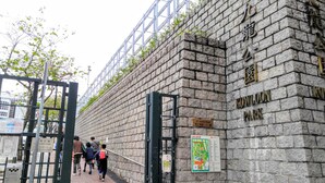A stone wall with a metal gate and a sign indicating Kowloon Park. - Nuts Hotel (Kowloon)