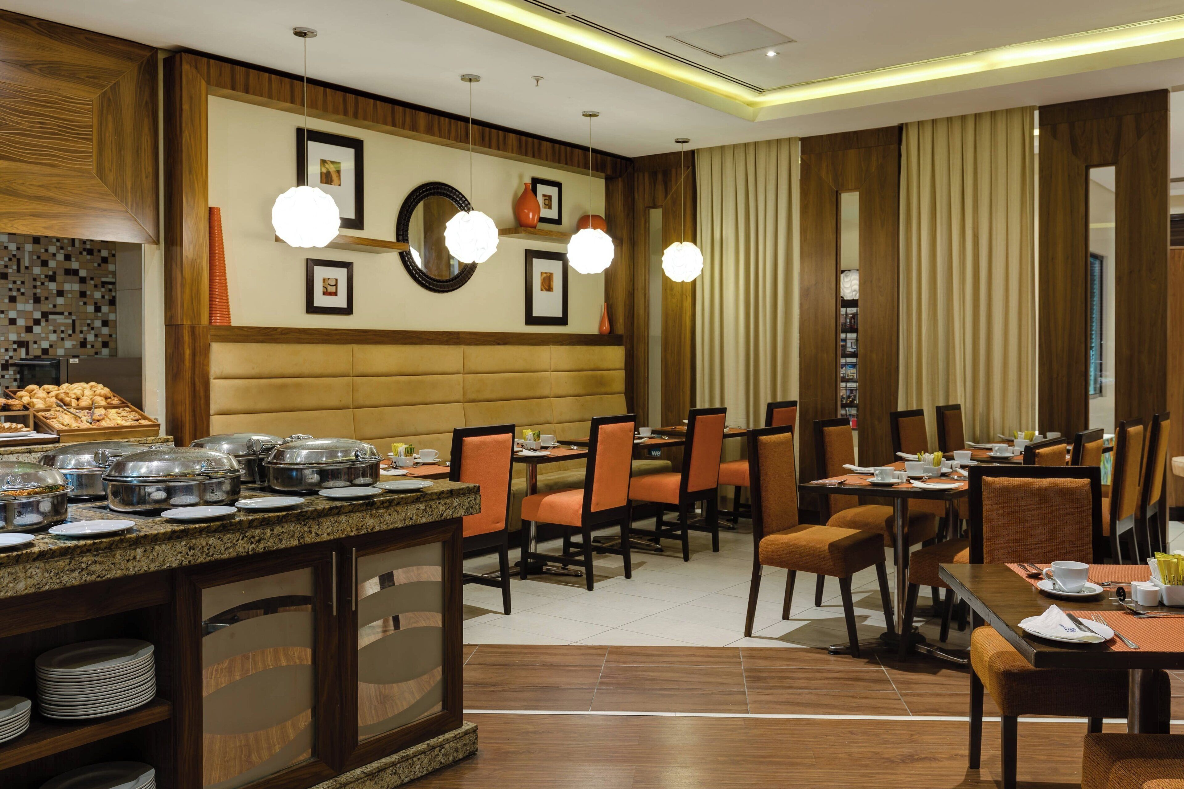 Een hotelrestaurant met buffetten, verschillende eettafels en stoelen.