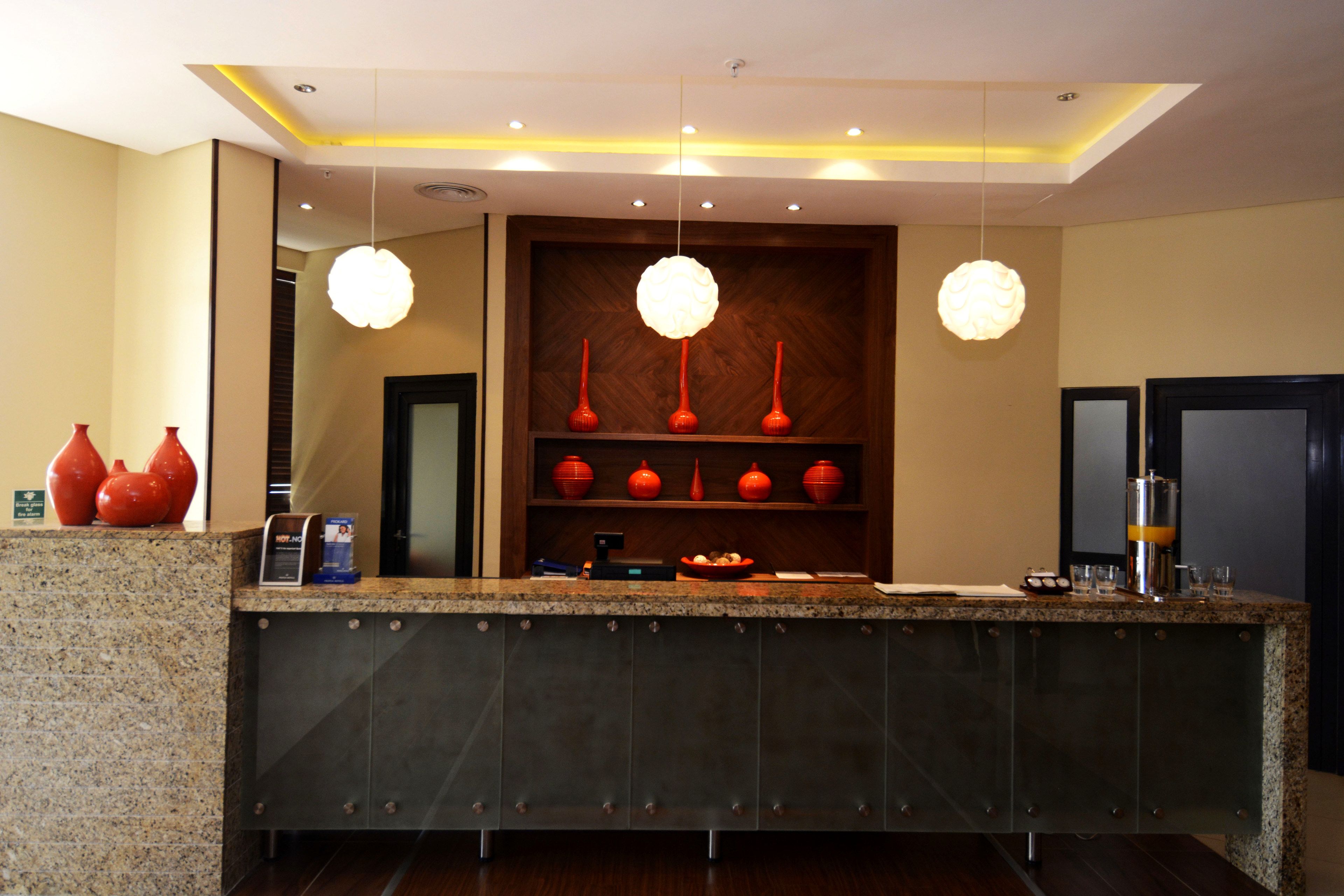 A reception area with a granite counter, three red vases on display, and a wooden panel wall.