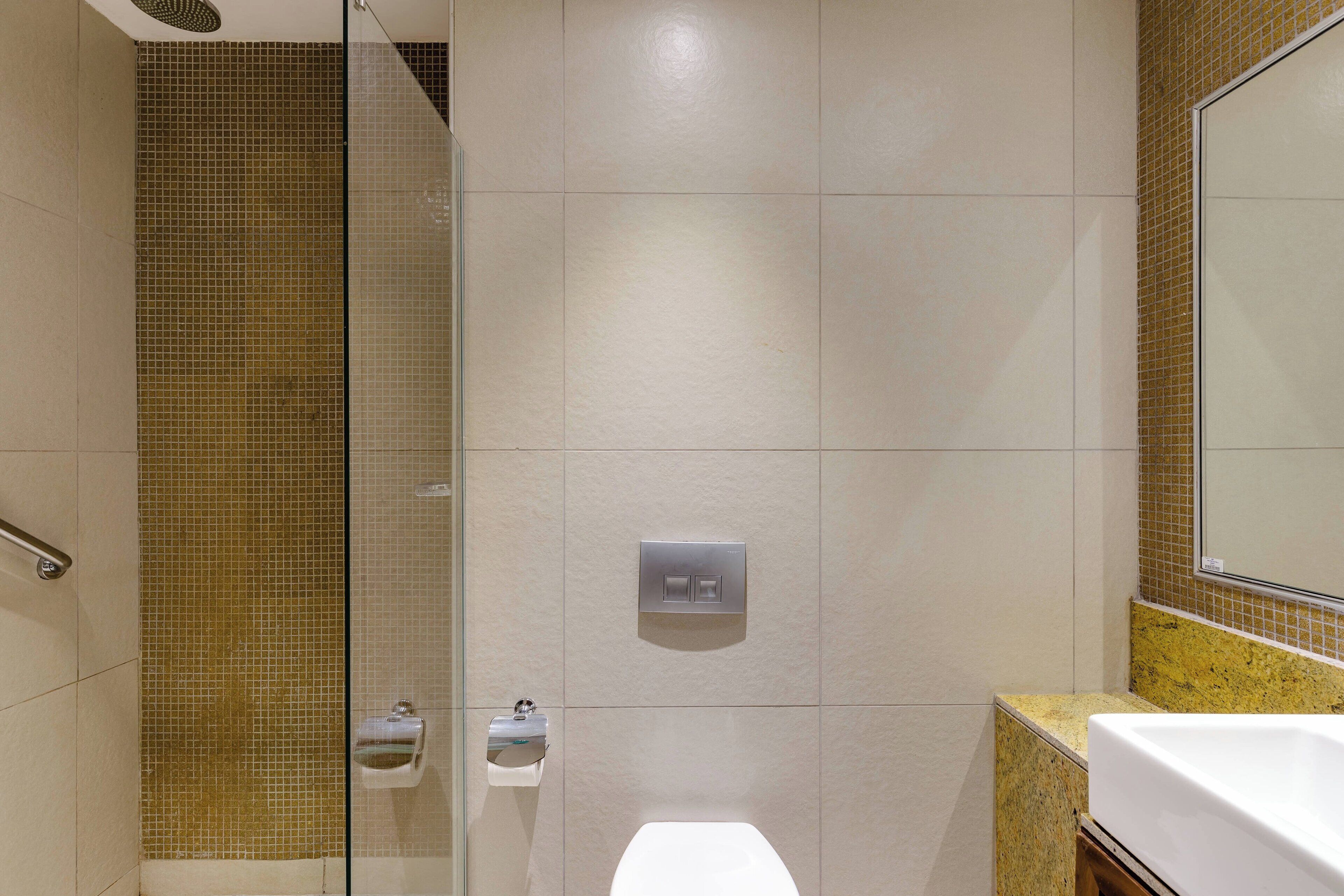 A bathroom with a glass shower enclosure, a toilet, and a sink with a mirror above it.