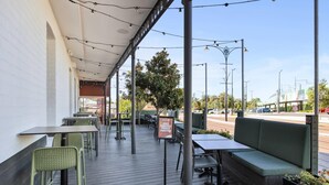 An outdoor patio with tables and chairs, a green bench, and a sign indicating a private function area. - Quality Hotel Bayswater (Bayswater)