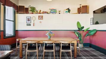 A dining area with a wooden table and chairs, a plaid carpet, and a wall decorated with books, trophies, and framed pictures.