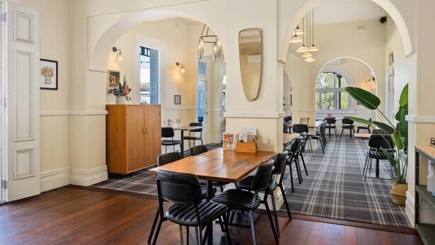 A spacious dining area with a long wooden table, black chairs, and a plaid rug. - Quality Hotel Bayswater (Bayswater)