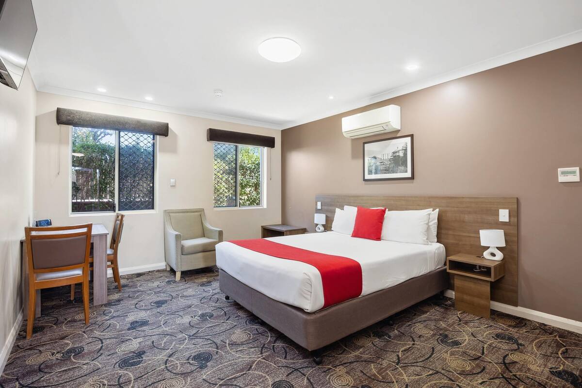 A hotel room with a large bed, a desk, and a chair.