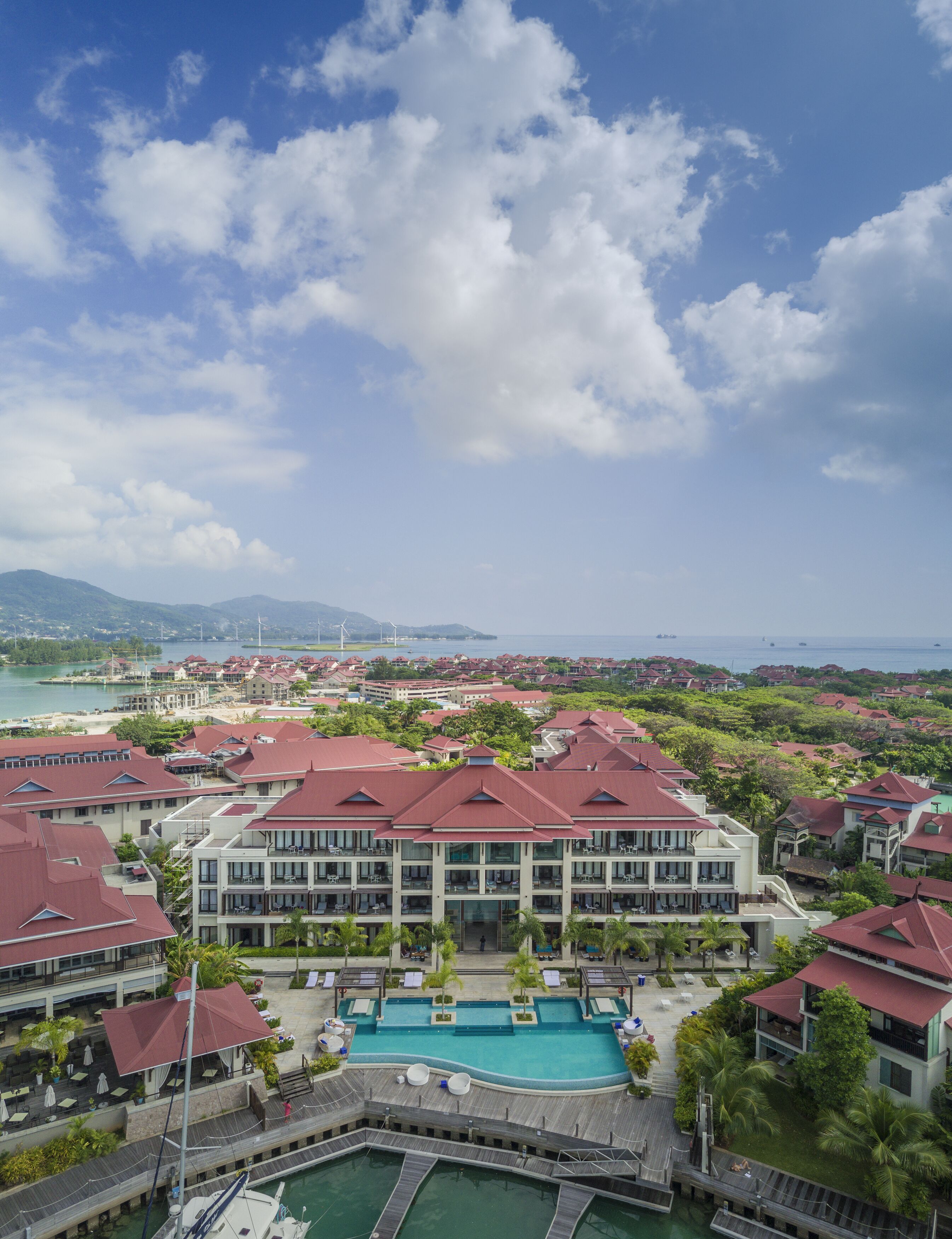 A resort with multiple buildings, a large swimming pool, and a dock with boats.
