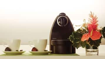 Una cafetera, dues tasses i una petita planta damunt un taulell.