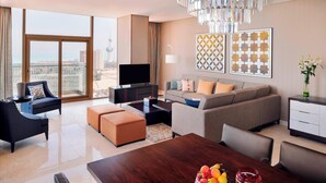 Una sala de estar moderna con un televisor grande, asientos cómodos y un comedor con un frutero.