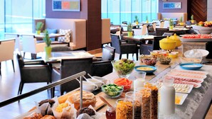 Un bufé con diversas opciones de comida y bebidas, como pasteles, ensaladas y fruta.