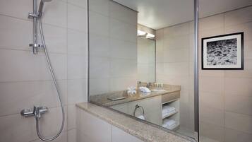 Un baño moderno con ducha, un espejo grande y un cuadro en la pared.