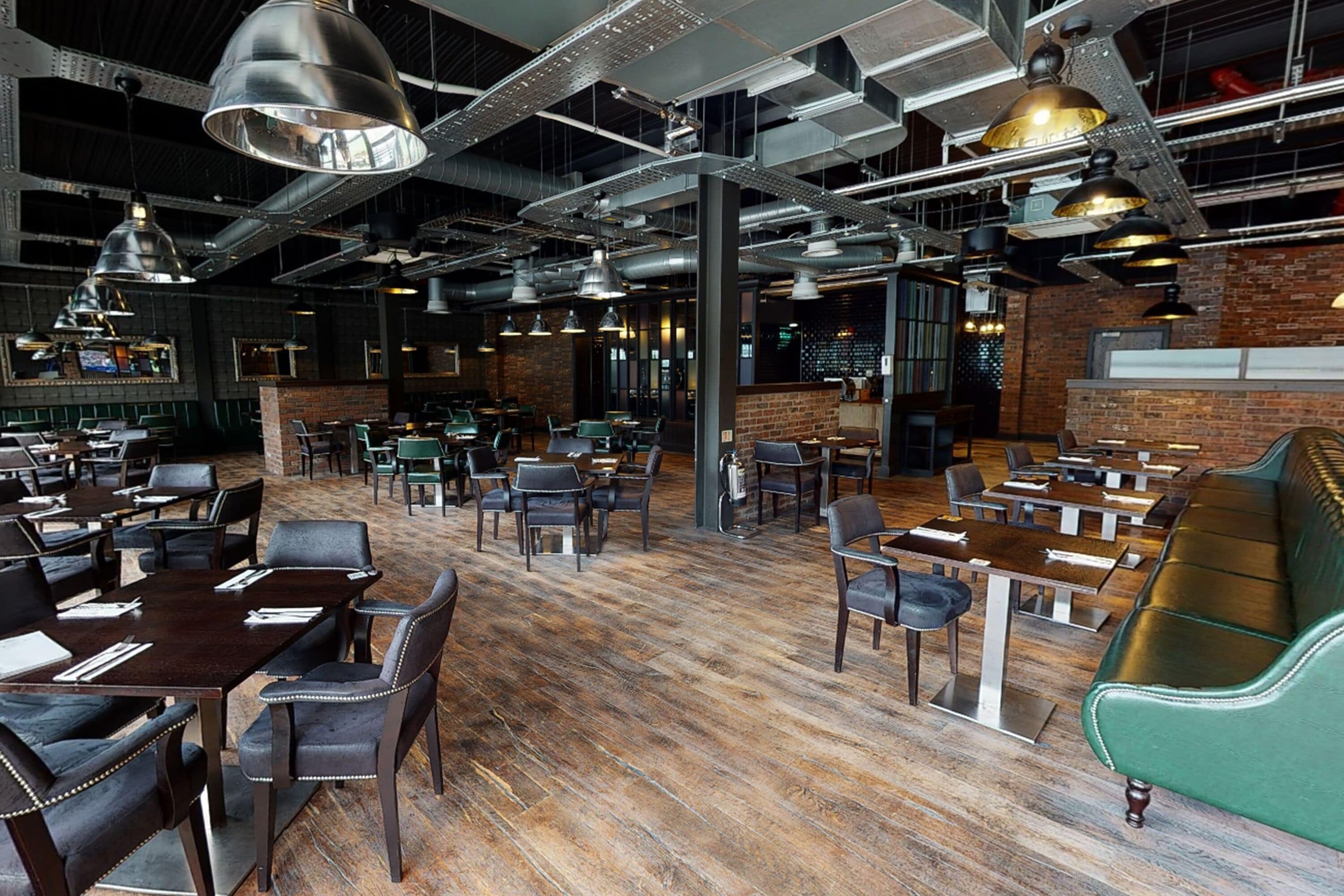 A spacious restaurant with high ceilings, exposed ductwork, and a mix of seating including tables and booths.