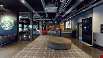 A modern interior with a Starbucks logo, a checkered floor, seating areas, and a staircase.