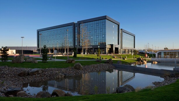 A modern building with a Starbucks Coffee on the ground floor, a pond with rocks, and a clear blue sky. - Village Hotel Aberdeen (Aberdeen)