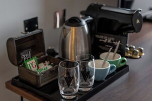 Una bandeja con dos vasos, una cafetera, una caja de cigarrillos PG y una taza sobre una mesa de madera.