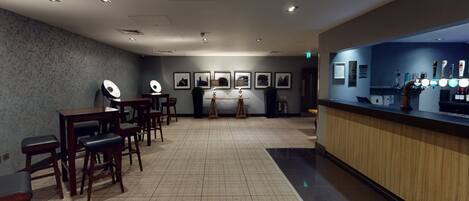 A hotel lobby with a reception desk, seating area, and framed pictures on the wall.