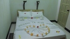 Una cama con un tapete de bienvenida, almohadas y un arreglo floral decorativo.