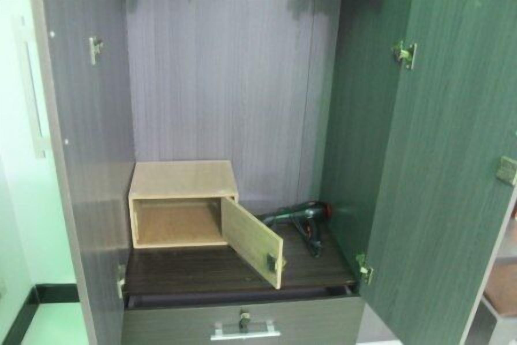 Una habitació amb un armari de fusta, una taula petita i una paret verda.