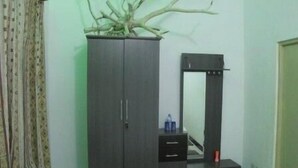 Una habitación con armario, espejo y una pequeña mesa con una botella de agua.