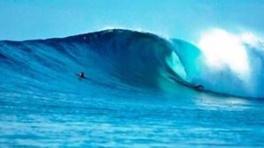 Una ola grande con un surfista montándola.