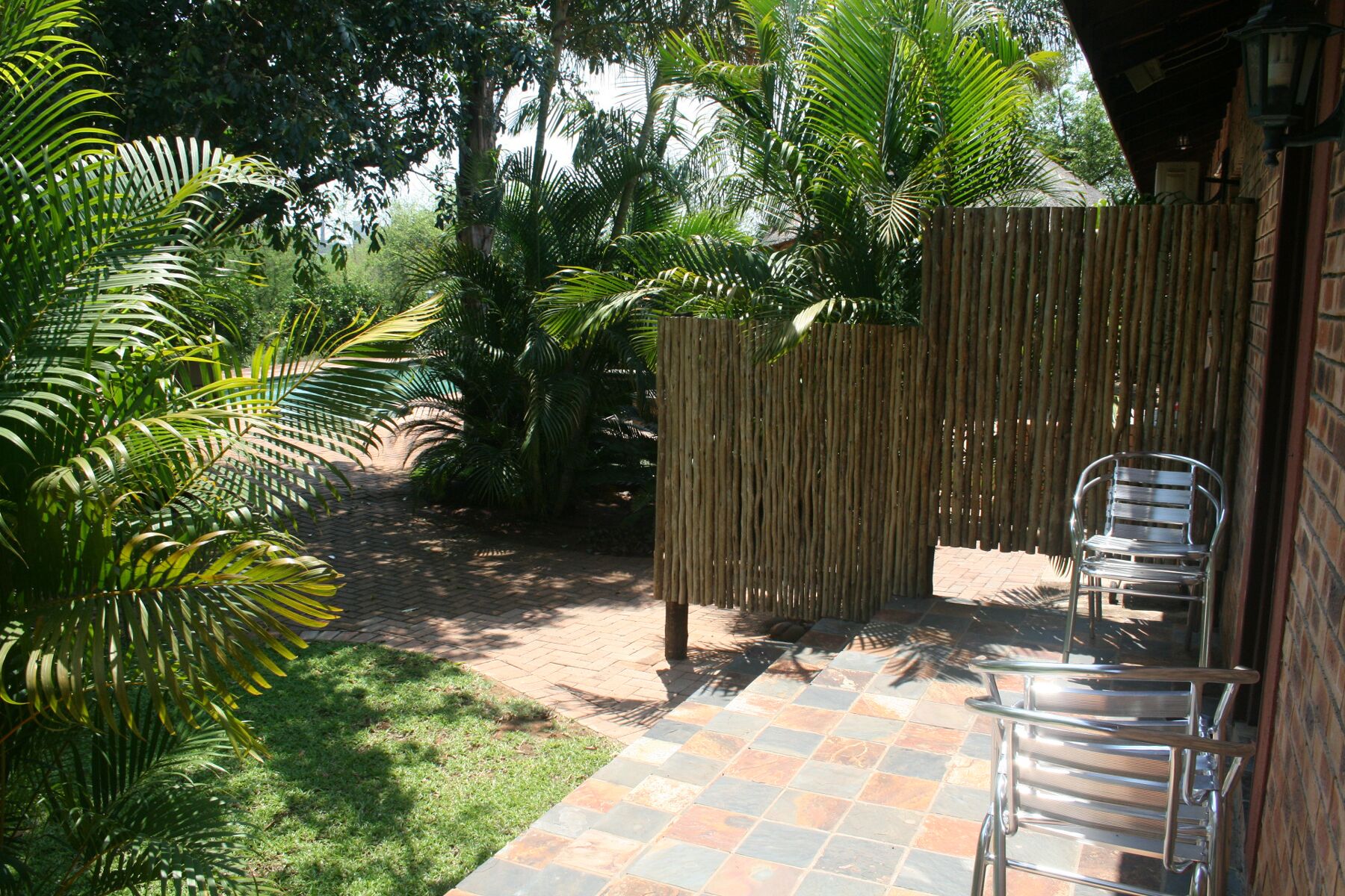 A patio area with a tiled floor, a bamboo fence, and a metal chair.