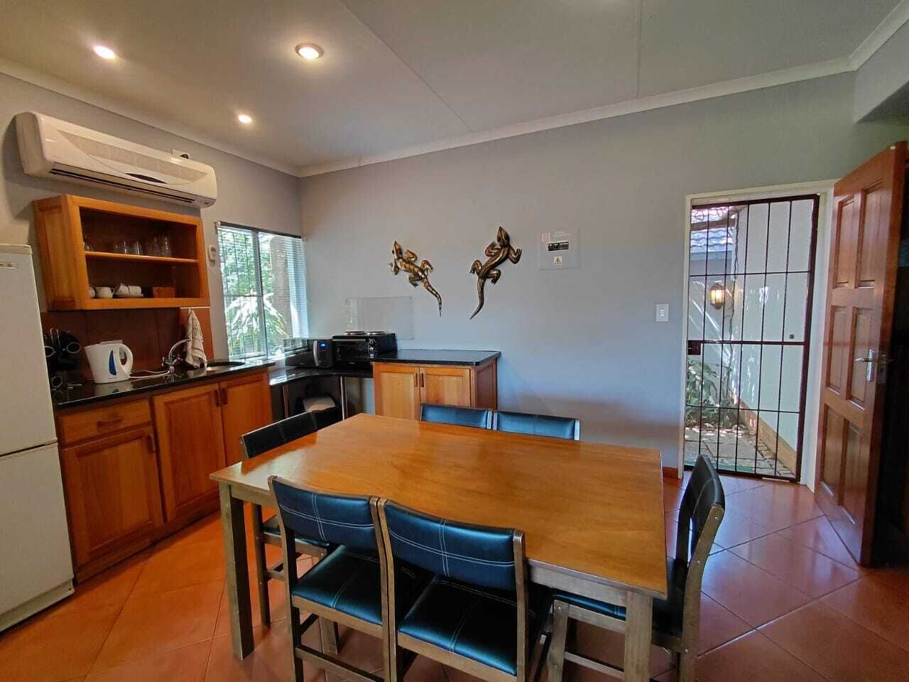 A dining area with a wooden table and blue chairs, a kitchen with wooden cabinets, and a sliding glass door leading outside.
