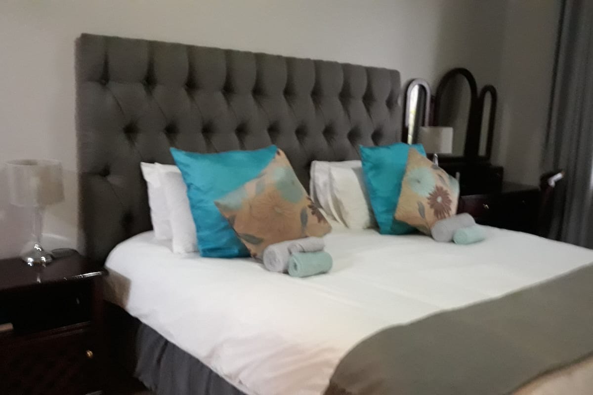 A neatly made bed with a tufted headboard, two pillows, and a blanket.