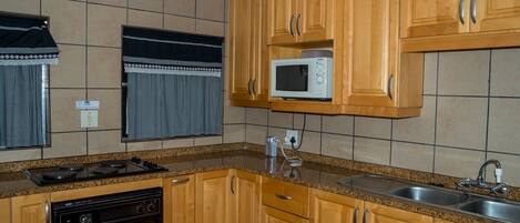 Una cocina con armarios de madera, microondas, estufa y lavavajillas.