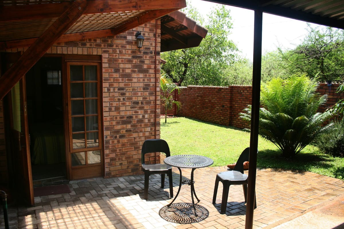 A patio with a brick wall, a wooden door, and a metal table with two chairs.