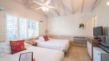 A hotel room with two beds, a ceiling fan, a TV, and a kitchenette.