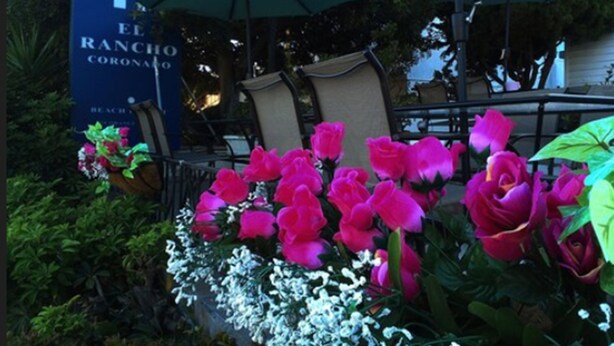 A dining area with outdoor seating, a sign reading "El Rancho Coronado," and a variety of flowers. - El Rancho Motel (Coronado)