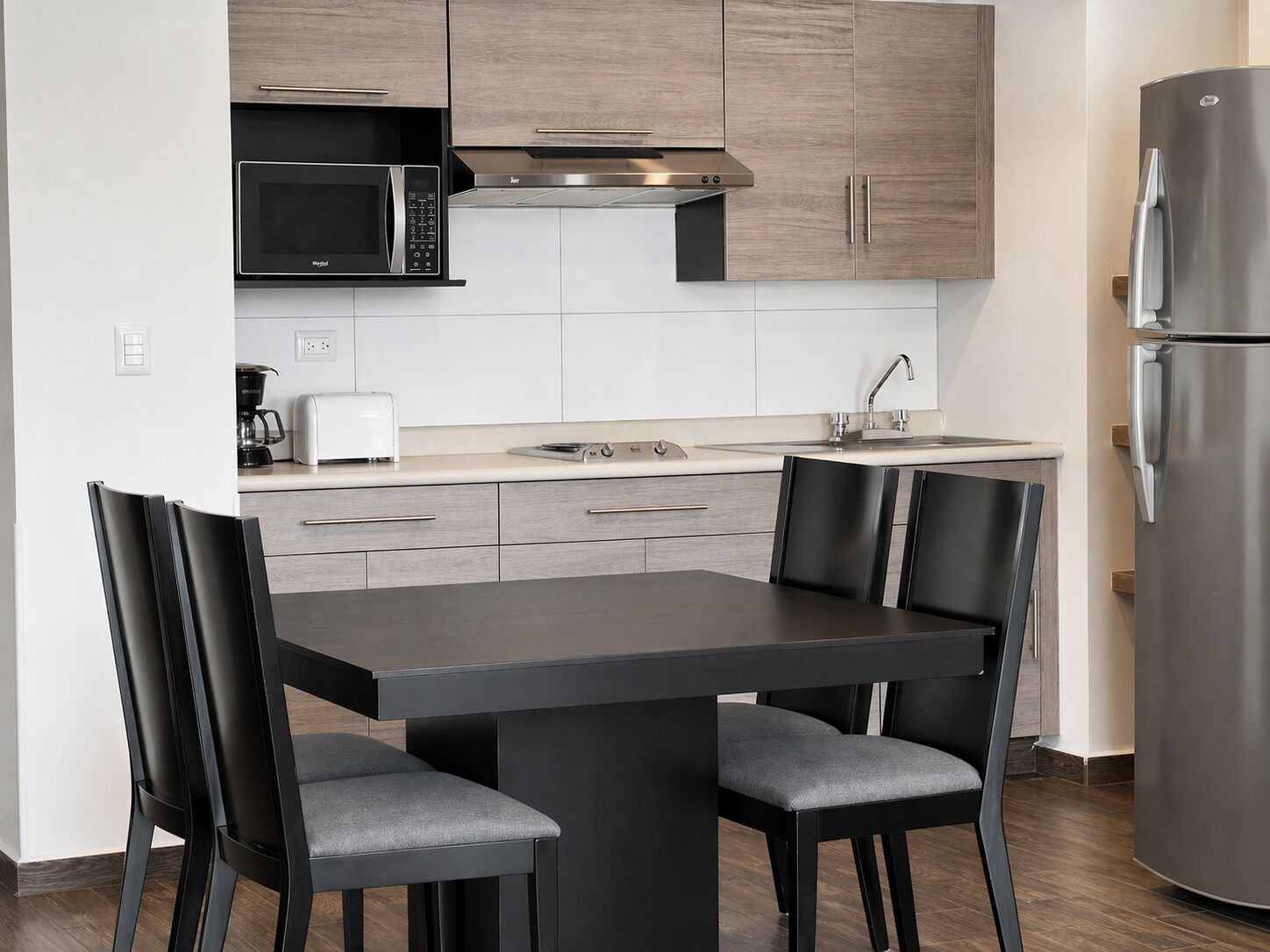 A modern kitchen with a built-in microwave, stove, and stainless steel refrigerator.
