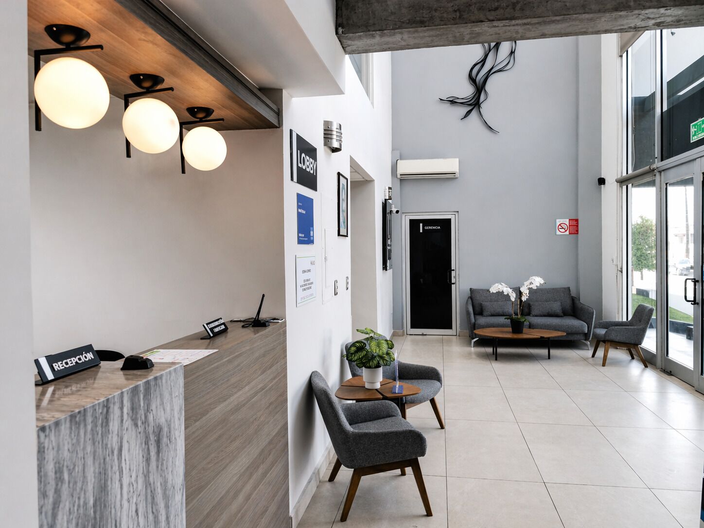 A modern reception area with a reception desk, seating, and a large window.