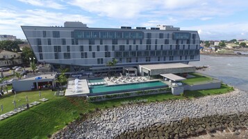 Un hotel moderno con piscina, zona de estar al aire libre y vistas al mar.