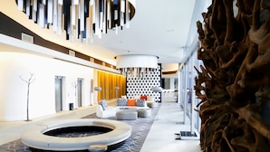 Een moderne lobby met een rond zitgedeelte, een unieke wandsculptuur en een kamerbreed tapijt met dessin.