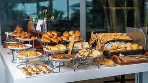 Een buffet met diverse gerechten, waaronder gebak, brood en desserts.