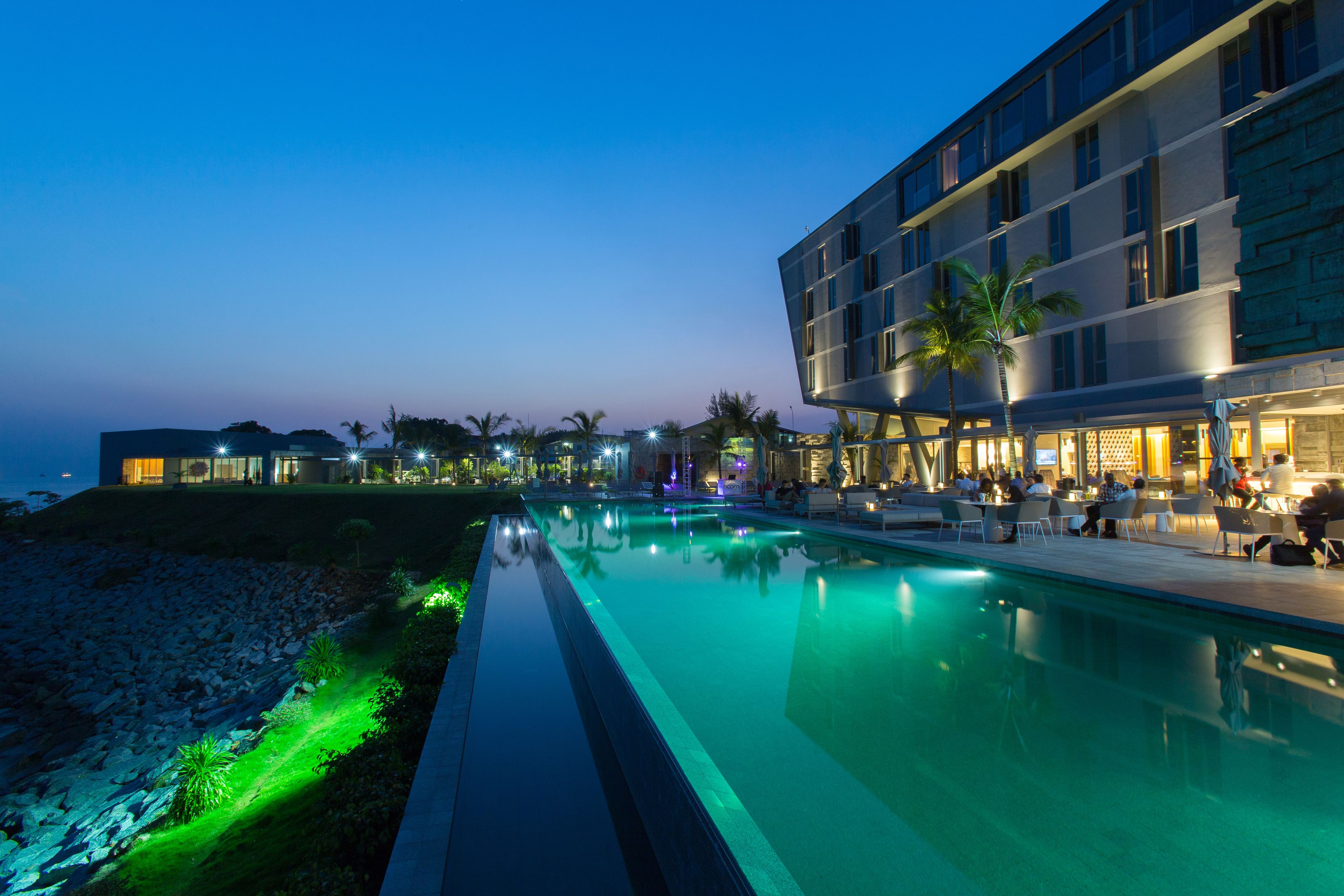 Een modern hotel met een zwembad, terras en uitzicht op zee.