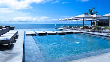 Una piscina al aire libre, sombrillas, sillones reclinables de piscina