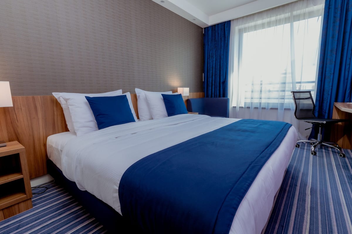 Ein Hotelzimmer mit einem großen Bett, einem Schreibtisch und einem Stuhl.