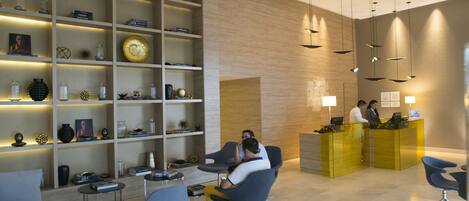 A modern reception area with a reception desk, seating area, and decorative shelves.