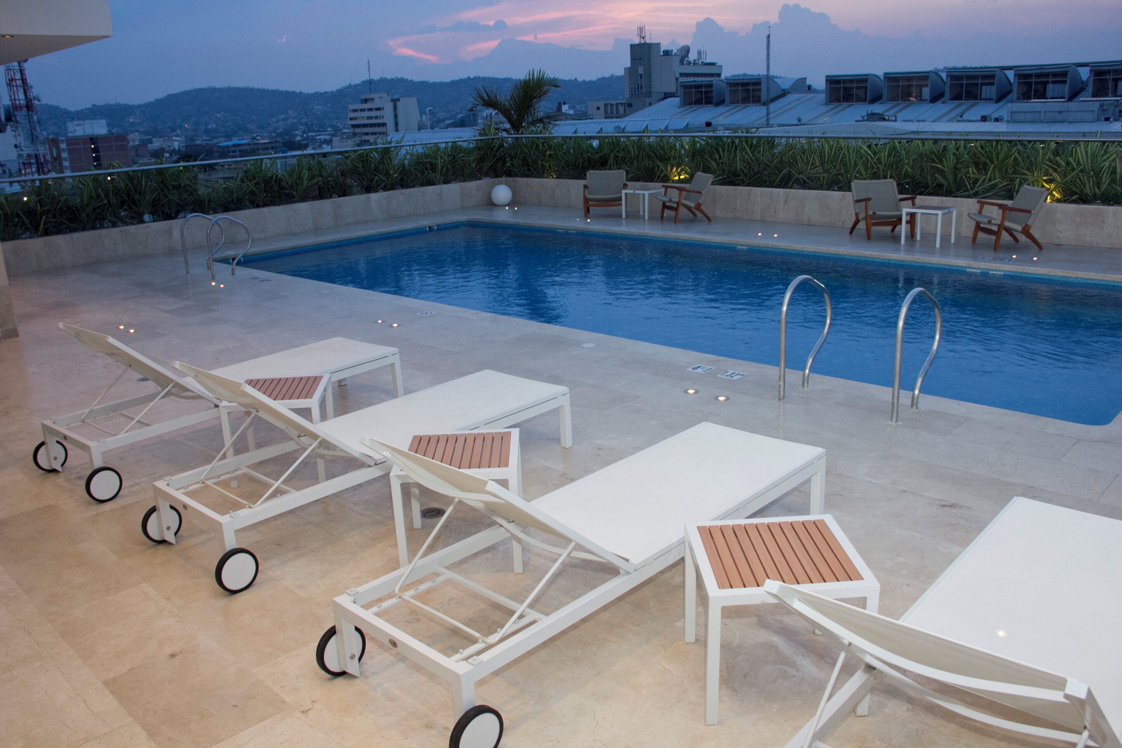 A rooftop pool area with lounge chairs and a swimming pool.