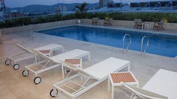 A rooftop pool area with lounge chairs and a swimming pool.