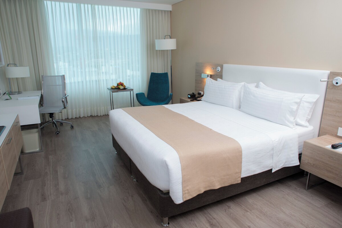 A hotel room with a bed, a desk, a chair, and a nightstand.