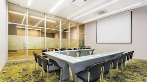 Un salón de conferencias con una larga mesa, sillas y una pantalla para proyector.