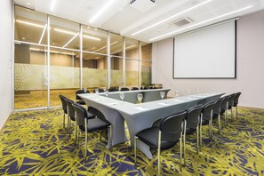 Une salle de conférence équipée d’une longue table, de chaises et d’un écran de projection.